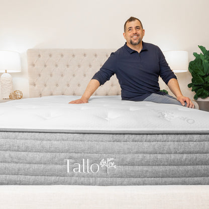 Man sitting on Tallo Classic Mattress, smiling, relaxed, comfortable sleep, organic mattress, eco-friendly materials, supportive mattress, happy customer